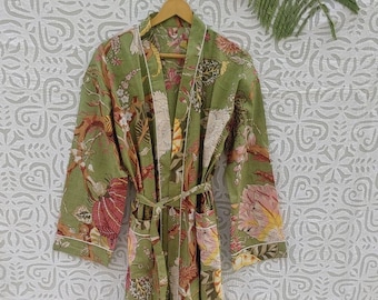 Peut inclure: Une robe de chambre à imprimé floral vert avec une bordure blanche et une ceinture à nouer. La robe est suspendue à un cintre en bois sur un fond blanc à motif floral.