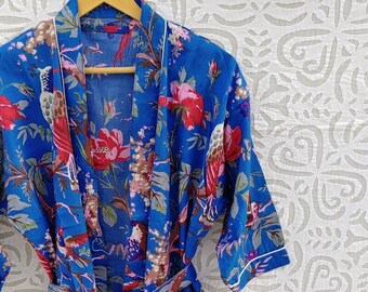 Puede incluir: Una bata de algodón azul con estampado floral con pájaros y flores. La bata tiene un cinturón de atar y dos bolsillos.