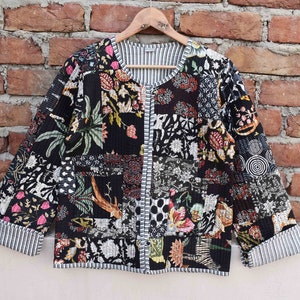 May include: A black quilted jacket with a floral print. The jacket has a button closure and long sleeves.