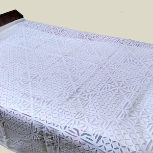 May include: White cotton bedspread featuring a delicate, intricate cut-out pattern. The pattern is a repeating geometric design with a floral motif.
