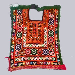 Puede incluir: Un panel de tela bordada de colores con un diseño geométrico que presenta círculos, cuadrados y triángulos. El panel está decorado con pequeños espejos y tiene un borde verde.