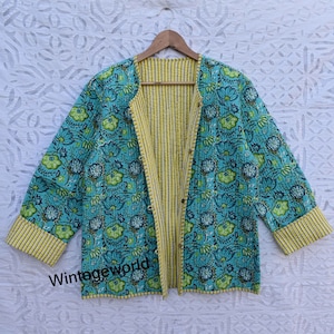 Könnte beinhalten: Eine gesteppte Jacke mit floralem Muster in Türkisblau und Grün mit gelben, gestreiften Besätzen und einem gelben, gestreiften Futter. Die Jacke hat einen Knopfverschluss und lange Ärmel.
