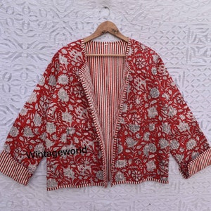 May include: Red and white floral print quilted jacket with a striped lining. The jacket has a long sleeve and a button closure.