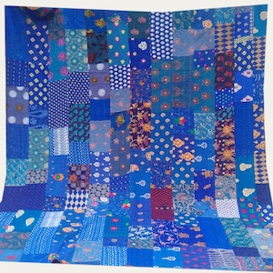 May include: A blue patchwork quilt with a variety of patterns and colors. The quilt is made of many different pieces of fabric sewn together.