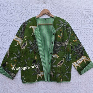 Puede incluir: Una chaqueta acolchada verde con forro a rayas y cierre de botones. La chaqueta presenta un estampado de cebras, leopardos y pájaros en un entorno de jungla. El texto "Vintageworld" está impreso en la parte delantera de la chaqueta.
