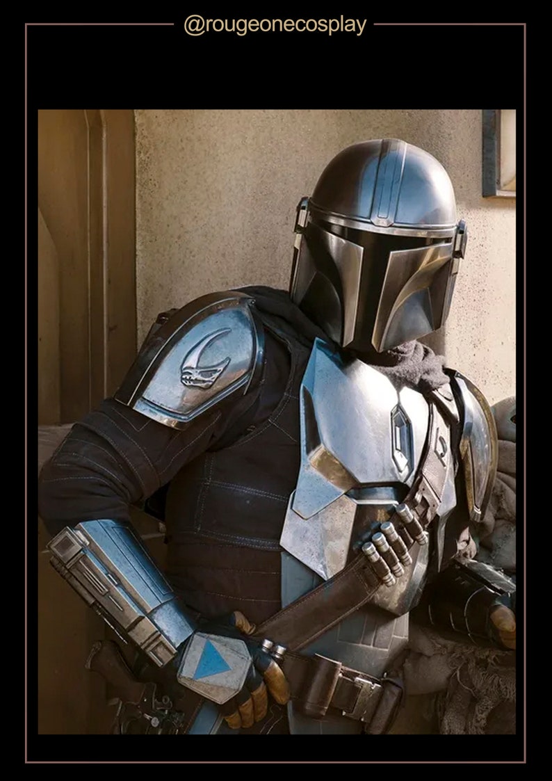 May include: A silver and black Mandalorian helmet with a visor. The helmet is worn by a person in a black and silver suit of armor. The armor has a symbol on the shoulder.