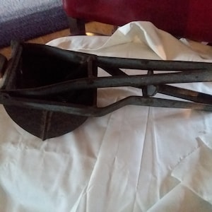 May include: A vintage metal hand-crank apple peeler with a black finish. The peeler has a handle and a crank that rotates a blade to peel apples.