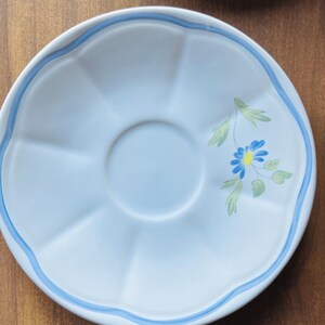 May include: A white saucer with a blue rim and a blue and yellow floral design.