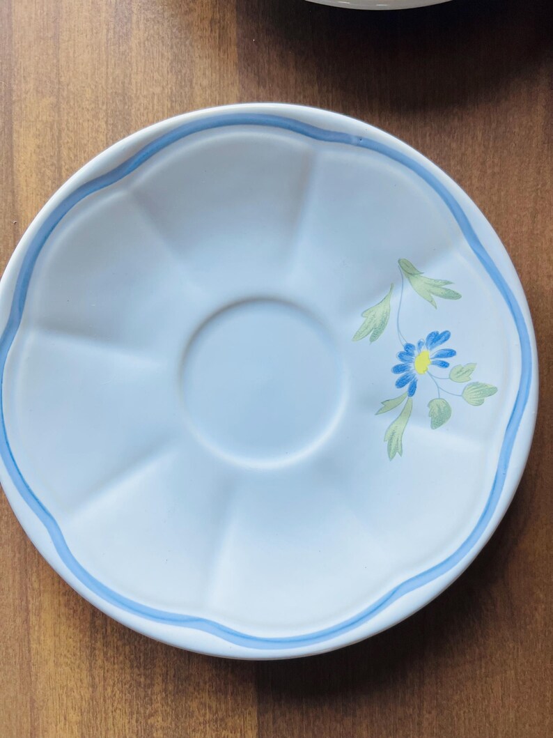May include: A white saucer with a blue rim and a blue and yellow floral design.