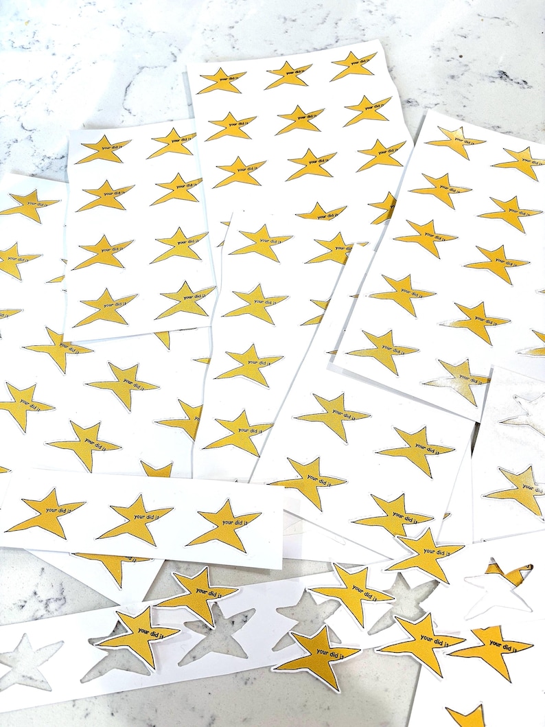 May include: A sheet of stickers with yellow star shapes and the text "Your did it" printed on each star. The stickers are arranged in rows and columns on a white surface.