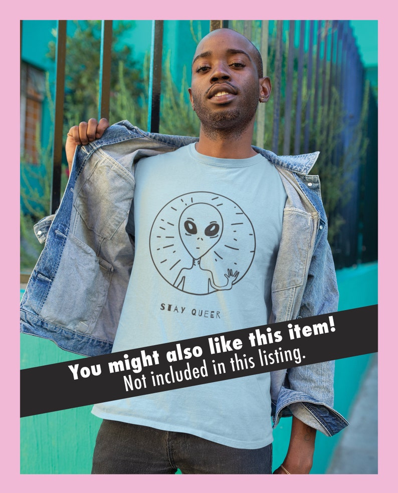 K&ouml;nnte beinhalten: Ein hellblaues T-Shirt mit einer schwarzen und wei&szlig;en Grafik eines Au&szlig;erirdischen mit dem Text "STAY QUEER" darunter.