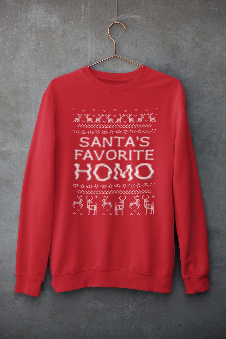 K&ouml;nnte beinhalten: Roter Weihnachtspullover mit einem wei&szlig;en pixelartigen Design von Rentieren und dem Text "SANTA'S FAVORITE HOMO".