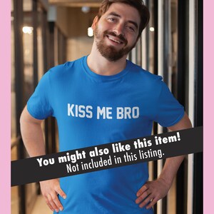 K&ouml;nnte beinhalten: Ein Mann tr&auml;gt ein blaues T-Shirt mit dem Aufdruck "KISS ME BRO" in wei&szlig;.