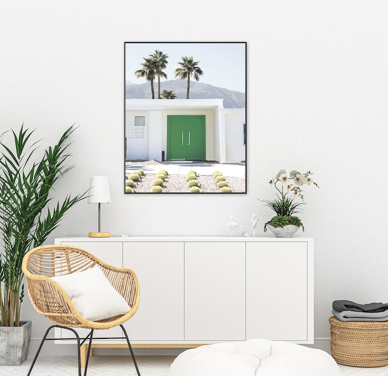 May include: A framed photograph of a modern, white house with a bright green door. The house is surrounded by palm trees and a gravel driveway.