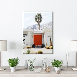 May include: A framed photograph of a white house with a bright orange door. The house has a palm tree in front of it and a mountain range in the background. The house number is 2285.