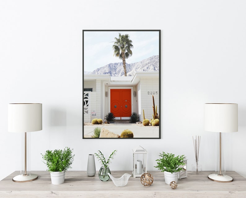 May include: A framed photograph of a white house with a bright orange door. The house has a palm tree in front of it and a mountain range in the background. The house number is 2285.