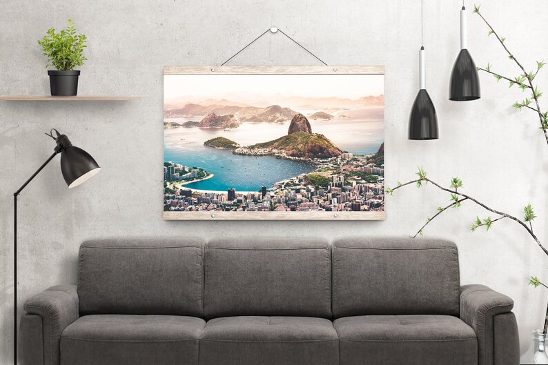 May include: A framed photograph of a city skyline with a large mountain in the background. The city is located on a peninsula with a body of water surrounding it. The photograph is in a wooden frame with a white background.