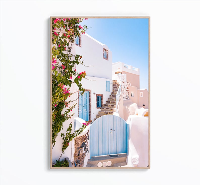 Puede incluir: Un edificio blanco con una puerta azul y una escalera de piedra que conduce a &eacute;l. Flores rosas crecen en una vid frente al edificio.