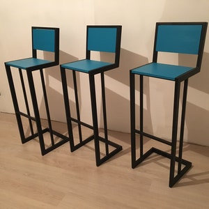 Puede incluir: Tres taburetes de bar de metal negro con asientos azul turquesa. Los taburetes tienen un diseño simple y moderno.