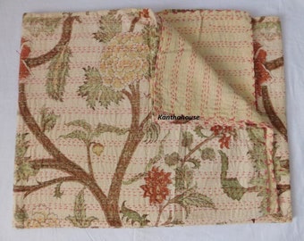 May include: A cream-colored kantha quilt with a floral pattern in shades of green, brown, and orange. The quilt is folded in half and has a hand-stitched design.
