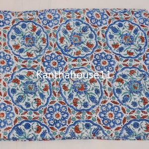 May include: White cotton fabric with a repeating pattern of blue and red floral motifs in a circular design. The fabric has a vintage, distressed look. The text "Kantha house11" is visible in the centre of the fabric.