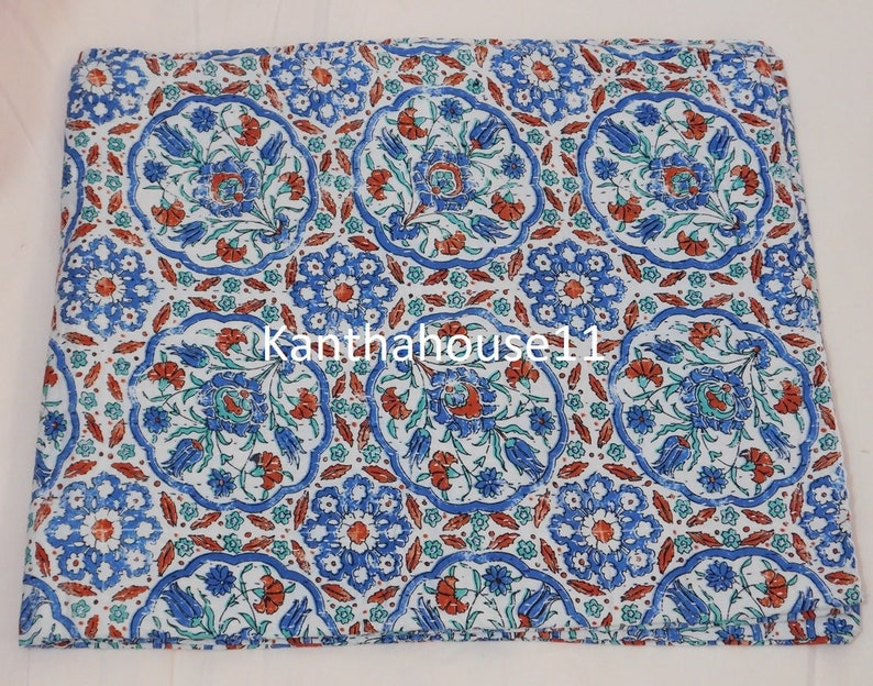 May include: White cotton fabric with a repeating pattern of blue and red floral motifs in a circular design. The fabric has a vintage, distressed look. The text "Kantha house11" is visible in the centre of the fabric.