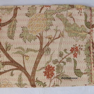 Puede incluir: Una colcha kantha de color crema con un patr&oacute;n floral en tonos verdes, marrones y naranjas. La colcha est&aacute; cosida a mano y tiene un borde deshilachado. El texto "Kantha House" es visible en la esquina inferior derecha.