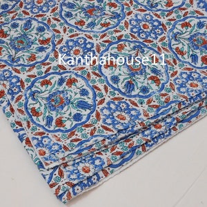 May include: A stack of white fabric napkins with a blue and red floral pattern. The pattern features stylised flowers and leaves in a repeating design.