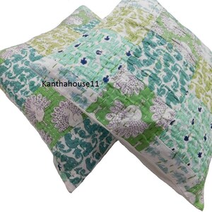 May include: Two green and white patterned throw pillows with a peacock design. The pillows are made of cotton and have a quilted texture.