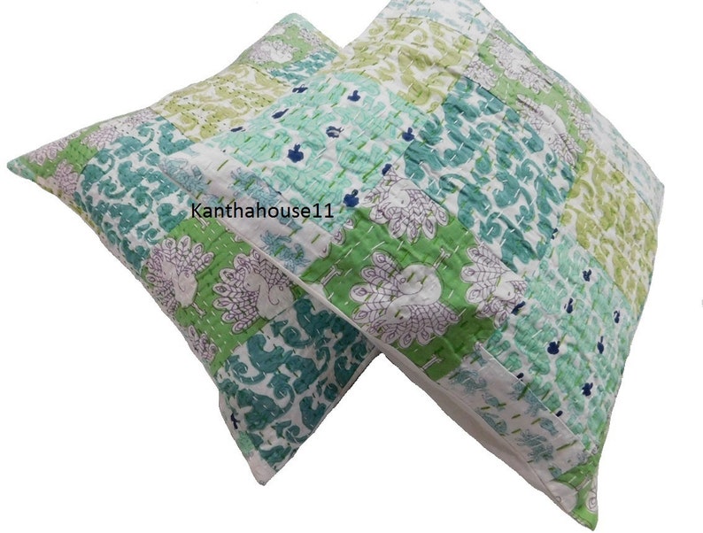 May include: Two green and white patterned throw pillows with a peacock design. The pillows are made of cotton and have a quilted texture.