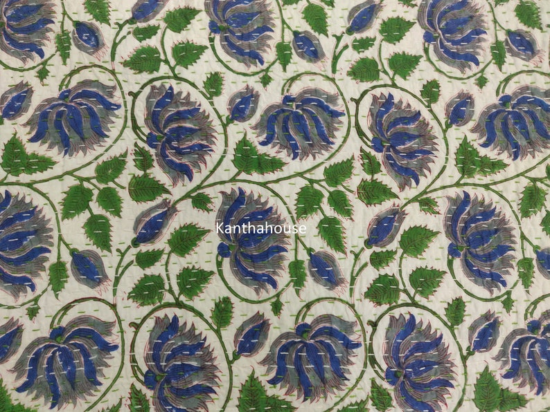 May include: A white fabric with a blue and green floral pattern. The fabric is quilted with a running stitch. The text "kantha house" is visible in the center of the image.