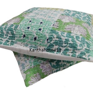 May include: A green and white patchwork cushion cover with a floral pattern. The cushion cover is made of cotton and is hand-stitched. The text "Kantha house11" is visible on the cushion cover.