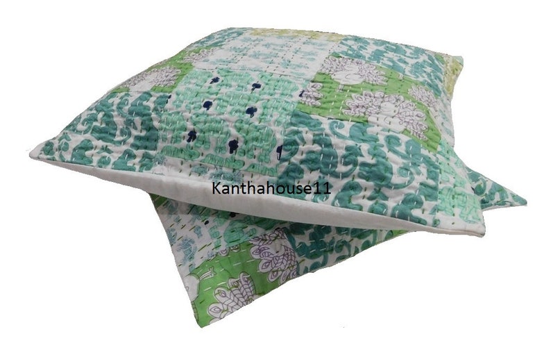 May include: A green and white patchwork cushion cover with a floral pattern. The cushion cover is made of cotton and is hand-stitched. The text "Kantha house11" is visible on the cushion cover.