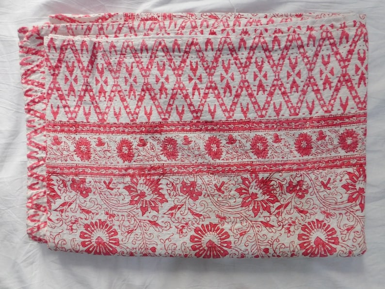 Op de afbeelding: Een wit katoenen dekbed met een roze bloemenpatroon. Het dekbed heeft een rand met een geometrisch ontwerp.
