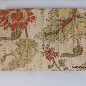 Puede incluir: Una colcha kantha beige con un patr&oacute;n floral en tonos de verde, marr&oacute;n y naranja. La colcha tiene un sutil patr&oacute;n de puntos rosas y el texto "Kantha House" es visible en la esquina inferior derecha.