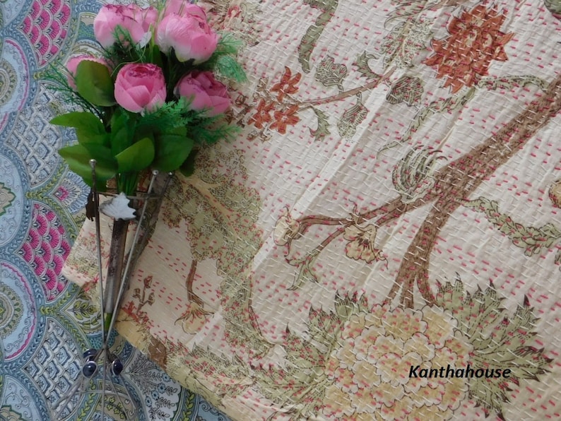 Puede incluir: Una colcha kantha blanca con un patr&oacute;n floral en tonos de rosa, verde y marr&oacute;n. La colcha est&aacute; cosida a mano y tiene una textura delicada. El texto "Kantha house" es visible en la esquina inferior derecha de la imagen.