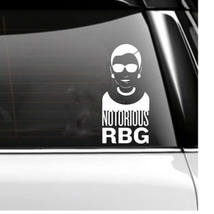 May include: White vinyl sticker with a black and white silhouette of Ruth Bader Ginsburg wearing glasses and the text "NOTORIOUS RBG".