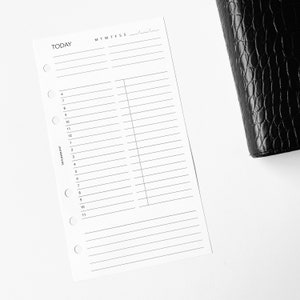 Peut inclure: Une feuille de planification blanche avec le mot "TODAY" en haut et une mise en page d'horaire. L'insert comporte des lignes pré-imprimées pour les créneaux horaires et les jours de la semaine. Un agenda en cuir noir est partiellement visible en arrière-plan.
