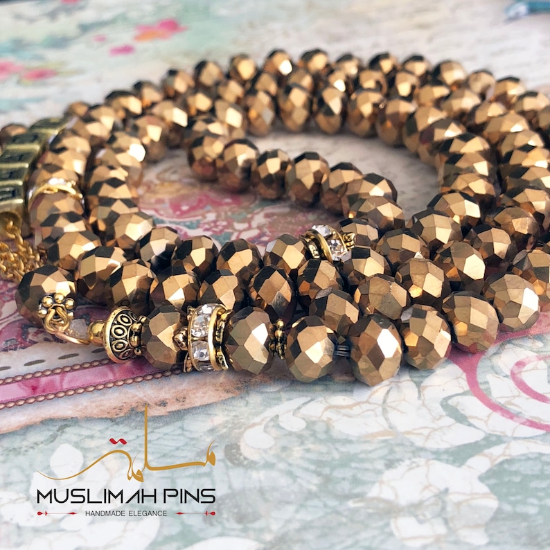 Op de afbeelding: Een gouden kralenketting met gefacetteerde kralen en gouden accenten. De ketting is gemaakt van meerdere strengen kralen en heeft een decoratieve sluiting.