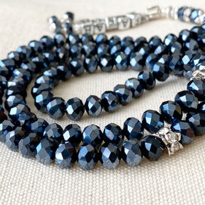 Op de afbeelding: Een donkerblauwe gebedsketting met zilveren accenten. De kralen zijn gefacetteerd en hebben een glanzende afwerking.