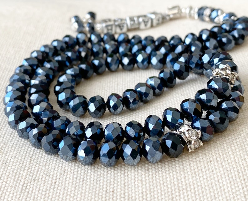 Op de afbeelding: Een donkerblauwe gebedsketting met zilveren accenten. De kralen zijn gefacetteerd en hebben een glanzende afwerking.