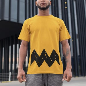 Peut inclure: Un t-shirt jaune avec un motif en zigzag noir sur le devant.