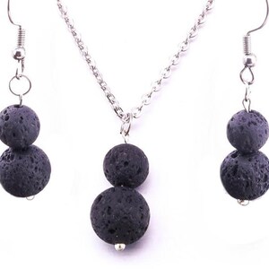 May include: A silver chain necklace and matching earrings with two black lava rock beads on each. The beads are round and have a rough, textured surface.