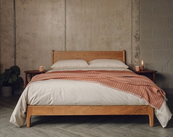 a handcrafted solid wood bed with peg-shaped legs and soft curves at the edges.