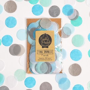 May include: A bag of 1 inch round blue, gray, and white confetti table sprinkles. The bag is labeled "Freshly Pressed" and "Table Sprinkles".