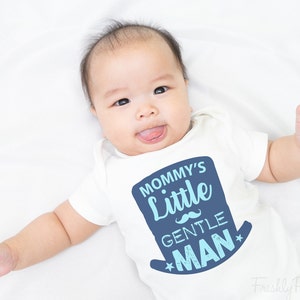 May include: A white baby onesie with a blue and light blue graphic that says "Mommy's Little Gentle Man" with a blue mustache and stars.