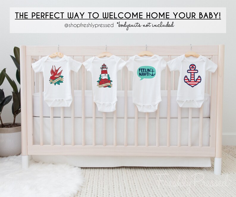May include: Four white baby onesies hanging on a white crib with nautical themed designs. The onesies feature a red bird with a banner that says "Welcome Home", a red and white lighthouse with the text "Sail Away", a speech bubble with the text "Feelin' Nauti", and a red and white anchor.