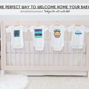K&ouml;nnte beinhalten: Vier wei&szlig;e Baby-Bodys h&auml;ngen an einem wei&szlig;en Babybett. Die Bodys haben verschiedene blaue und wei&szlig;e Designs mit Text, der "Totally Worth the Wait", "Crib Hair Don't Care", "Stud" und "Special Delivery" lautet.