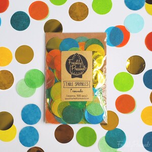May include: A bag of colorful confetti circles in various shades of green, blue, yellow, orange, and gold. The bag is labeled "Freshly Pressed" and "Table Sprinkles" with the text "1 rounds (approx. 500 pcs.) www.shopfreshlypressed.com".