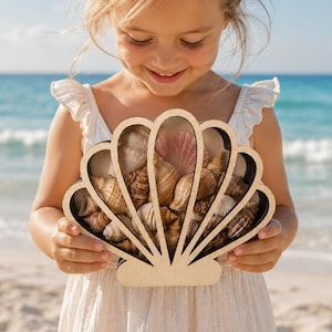 May include: A light-colored wooden display case shaped like a seashell, filled with a variety of small, natural tan and brown seashells. The frame of the display case is made of light wood and features a clear front panel to hold the shells inside.